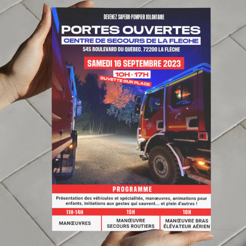 Deux mains tiennent une affiche qui décrit les portes ouvertes d'une caserne de pompiers, on voit sur l'affiche deux camions de pompiers de dos et les informations sur les événements prévus.